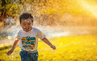 Bild: Ein Junge läuft durch eine Wasserfontäne